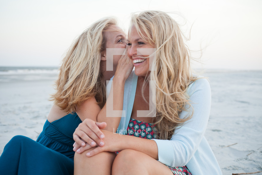 sisters talking and laughing on a beach 