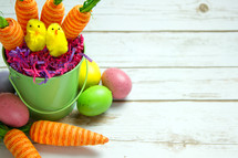 Easter eggs and carrot decorations in an Easter basket on white wood boards 