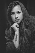 young woman in a hoodie with a forgiven tattoo