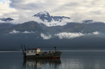 fishing boat on calm water and mountain view 