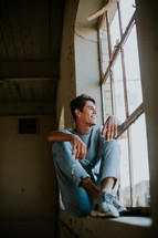 teen boy sitting in a window smiling 