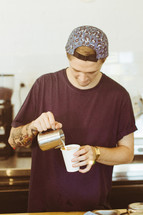 Man pouring creamer into his coffee.