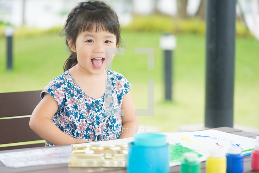Little Asian girl painting at park outdoor in school