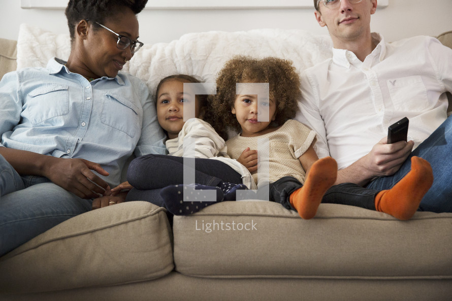 a family sitting on a couch watching tv together.