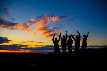 silhouettes of people with raised hands 