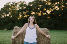 teen girl standing in front of a hay bale 