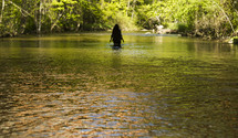 A woman wading in a river.