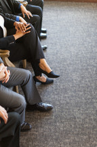 legs of businessmen and businesswomen sitting in chairs in meeting 