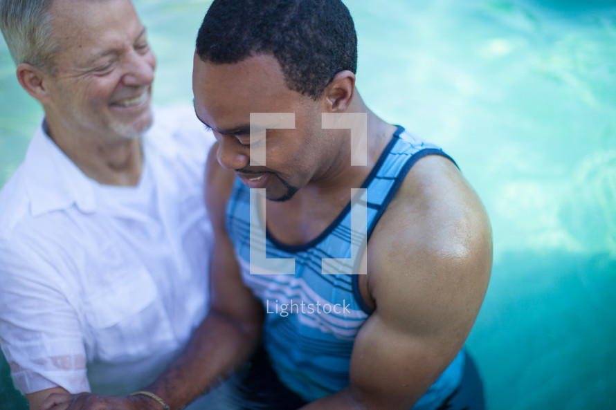 Man baptizing a man in a pool of water.