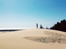 A man standing on a sand dune.