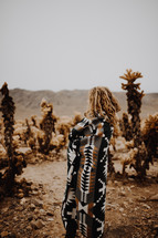 a woman wrapped in a blanket standing in a desert 