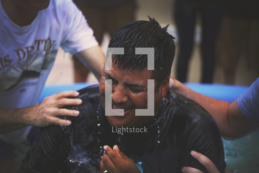 A man is lifted from a baptismal pool.