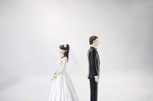 bride and groom figurines standing back to back.