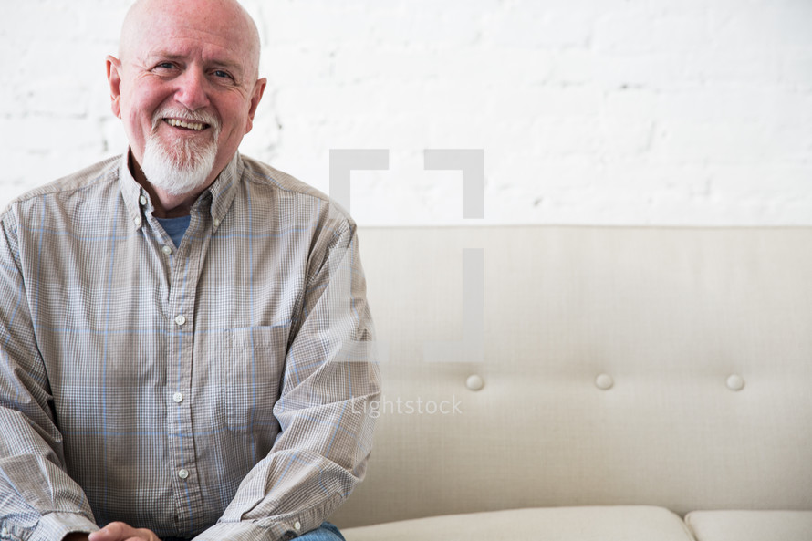 portrait of an elderly man sitting on a couch smiling