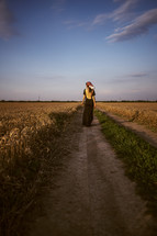 a woman standing on a dirt road 