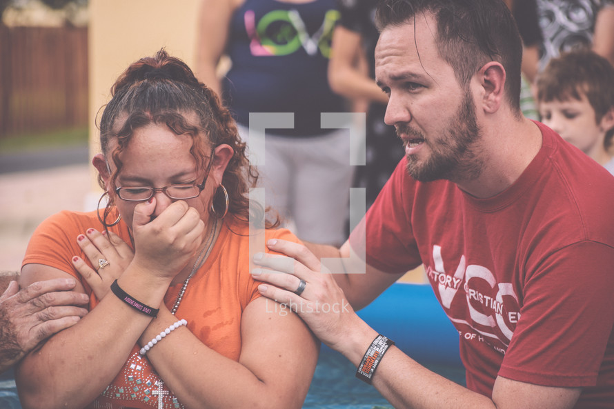 A woman preparing to be baptized by her pastor.