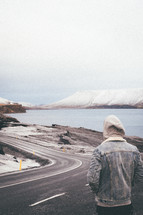 a man looking out at a winding road 