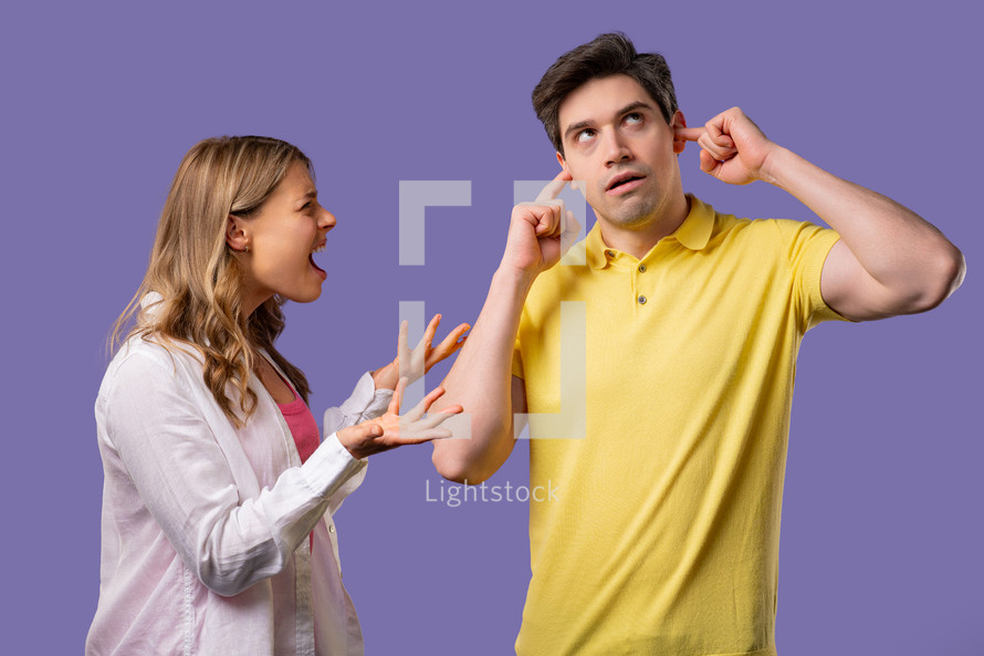 Young woman screaming on husband or boyfriend On violet. Tired man rolling eyes. Concept of conflict, quarrel, problems in couple relationships. High quality