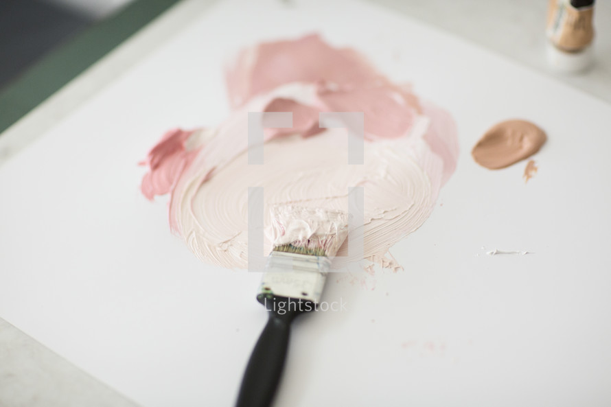 A paintbrush and paint on an artist's palette.