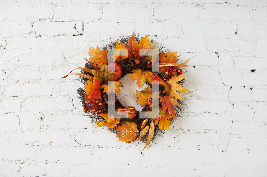 fall wreath on a white brick wall 