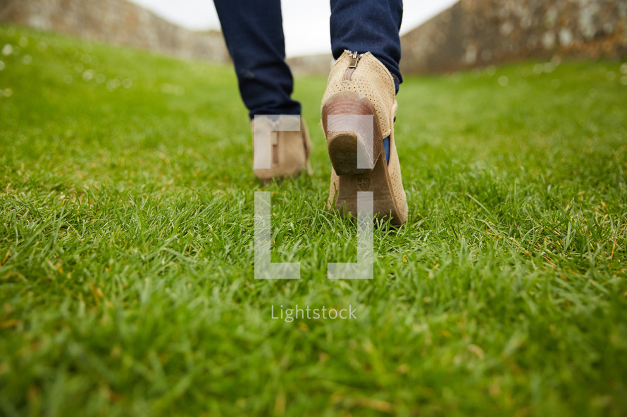 A woman in boots walking in grass