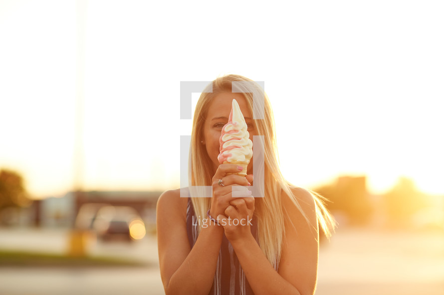 a woman holding an ice cream cone in front of her face 