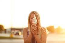 a woman holding an ice cream cone in front of her face 