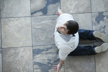 Aerial view of a man on his knees om tile, surrendering to God.