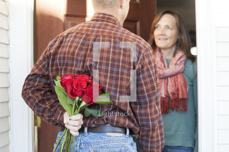 Man surprising his wife with flowers. 
