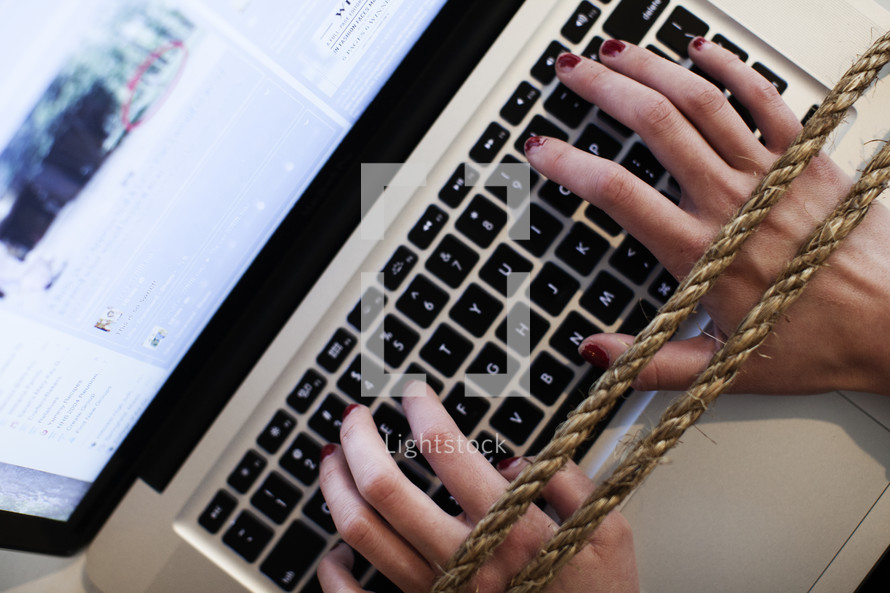 hands tied to a computer keyboard. Online addiction concept. 