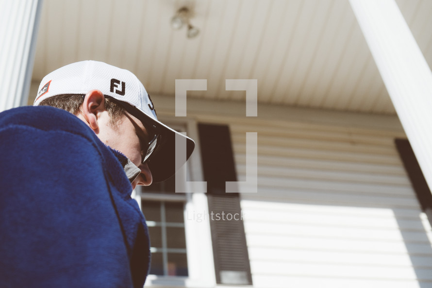 Man in a baseball cap on the front porch.