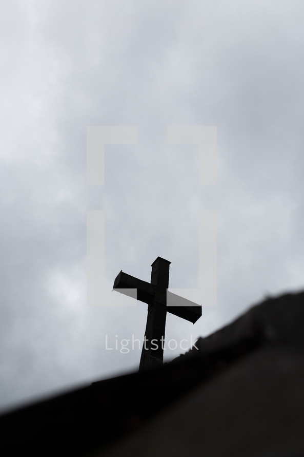 The silhouette of a cross against a gray sky.