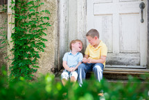 brothers laughing together sitting on steps outdoors 