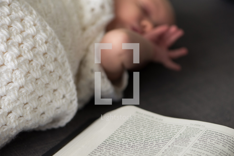swaddled newborn and open Bible 