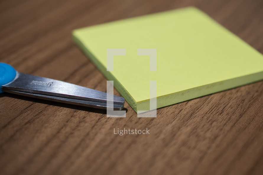 scissors and notepad on a wood table 