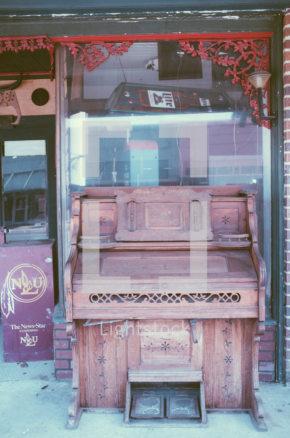 old piano in front of an antique store 