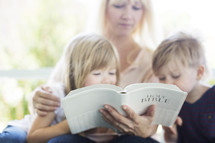 mother reading the Bible to her children 