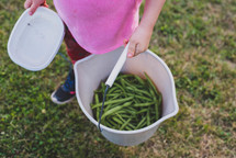 a girl with a bucket of green beans 