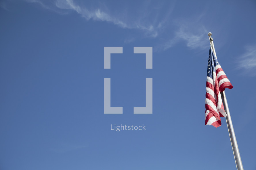 American flag on a flag pole with blue sky.
