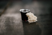 communion wine in a cup and bread on wood background 