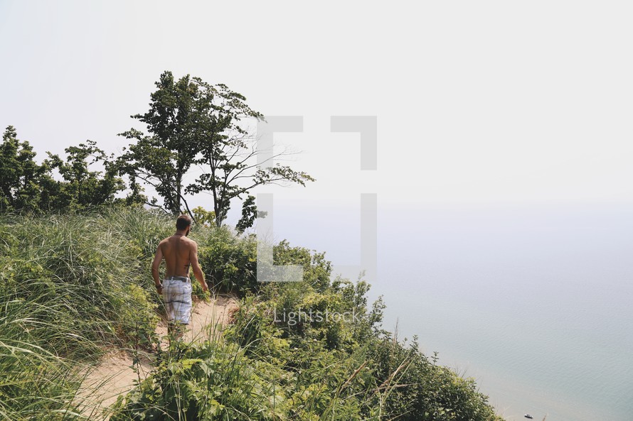 a man in a bathing suit walking to the edge of a cliff 