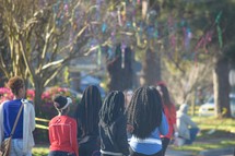 African American girls walking down a street under a tree covered in Mardi Gras beads 