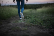 legs of a woman walking down a path 