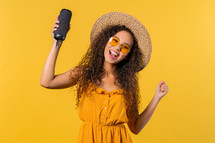 Woman dancing, enjoying on yellow studio background. Girl moves to rhythm of music. Young teenager listening to music by wireless portable speaker - modern sound system. High quality