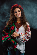 Modern young woman in traditional ukrainian handkerchief, necklace and embroidered blouse at multi-colors neon light smoke background. Ukraine, style, folk, culture. High quality photo