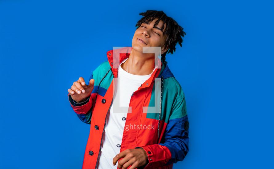 Energetic african american man dancing on blue background. Portrait of stylish guy with dreadlocks . High quality photo