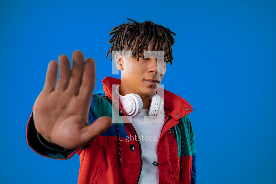 Serious african man showing rejecting gesture by stop palm sign. Dont play with me. Guy isolated on blue background. High quality. High quality photo