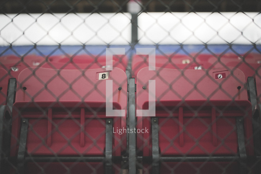 Stadium seats behind a chain link fence.