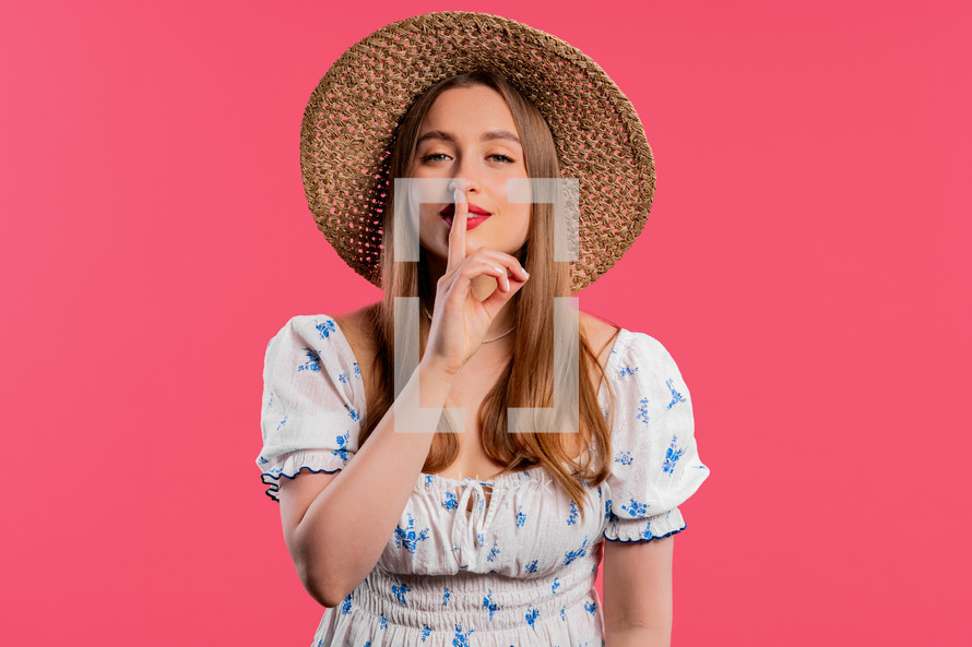 Smiling ukrainian woman holding finger on lips, pink studio background. Pretty lady with gesture of shhh, secret, silence, conspiracy, gossip concept. High quality