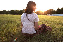 a woman sitting in a field 
